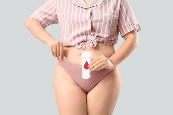 жінка в трусиках тримає гігієнічну прокладку